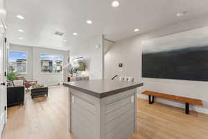 Kitchen featuring light wood finished floors, dark countertops, a kitchen island, recessed lighting, and baseboards