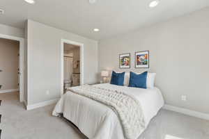 Bedroom featuring light colored carpet, recessed lighting, baseboards, and ensuite bathroom