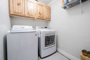 Washroom with washer and dryer, cabinet space, and baseboards