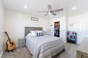 Bedroom with light carpet, a walk in closet, recessed lighting, baseboards, and a closet