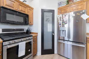 Kitchen with appliances with stainless steel finishes, brown cabinetry, light countertops, and light wood finished floors