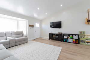 Living room featuring lofted ceiling, wood finished floors, baseboards, and recessed lighting