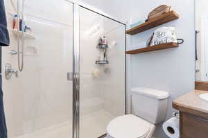 Full bath featuring toilet, a stall shower, and vanity