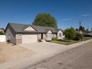 Ranch-style home with a garage, brick siding, driveway, and a shingled roof