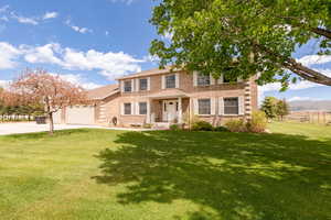 View of front of property with concrete driveway, brick siding, an attached garage, and a front lawn