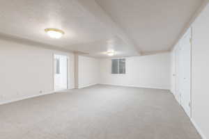 Unfurnished bedroom with light carpet, baseboards, and a textured ceiling