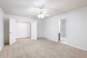 Unfurnished bedroom with carpet, baseboards, a closet, and ensuite bath