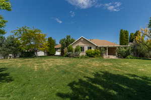 Rear view of property featuring a professionally landscaped yard