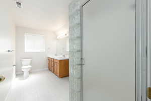 Full bathroom with toilet, a shower stall, baseboards, and double vanity