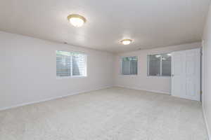 Large bedroom with light colored carpet, a textured ceiling, and baseboards