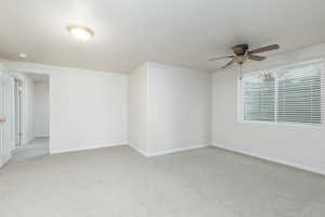 Spare room featuring a ceiling fan, light colored carpet, and baseboards