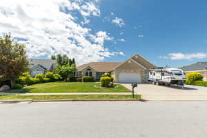 Ranch-style house featuring concrete driveway, an attached 3 car garage, a front lawn, and stone siding