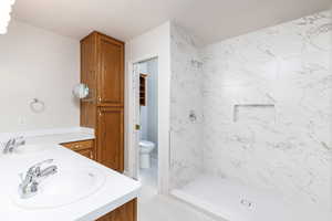 Full bathroom featuring a new shower,  double vanity, and toilet