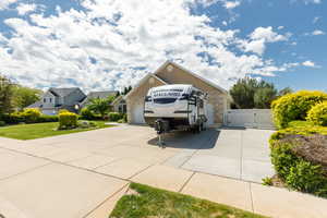 View of front facade featuring a gate, stone siding, concrete driveway, an attached 3 car garage, and a front yard