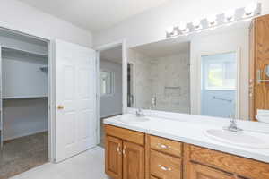Full bathroom featuring double vanity and a spacious closet