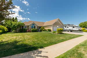 Single story home featuring concrete driveway, a front lawn, and a garage