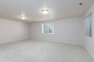 Large bedroom, featuring carpet, a textured ceiling, and baseboards