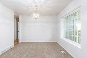 Carpeted office with a chandelier and baseboards