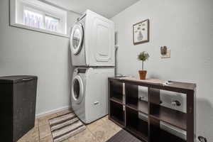 Washroom featuring estacked washer and dryer and light tile patterned floors