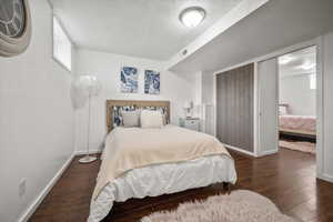 Bedroom with a textured ceiling, baseboards, and wood finished floors