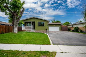 View of front facade featuring a garage, driveway, a porch, and stucco siding