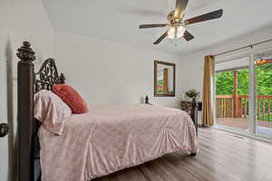 Bedroom with access to outside, wood finished floors, multiple windows, and a ceiling fan