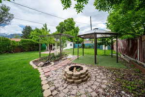 View of yard featuring an outdoor fire pit, a gazebo, a patio, and an outdoor structure