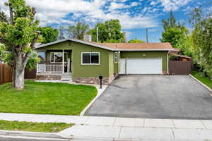 View of front of property with a porch, an attached garage, asphalt driveway, and stucco siding