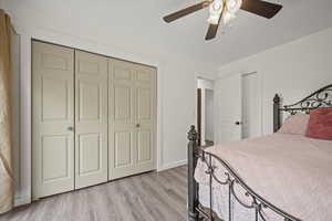 Bedroom featuring light wood-style floors, a ceiling fan, a closet, and baseboards
