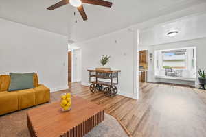 Living room with ceiling fan, wood finished floors, and baseboards