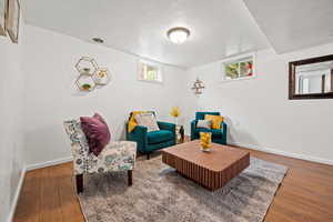Living area featuring wood finished floors, baseboards, and a textured ceiling
