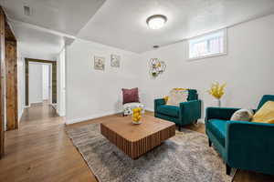 Living area featuring a textured ceiling, wood finished floors, and baseboards