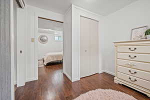 Bedroom with dark wood-type flooring, a closet, and baseboards