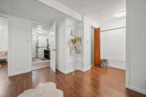Corridor featuring stacked washer and clothes dryer, hardwood / wood-style flooring, and baseboards