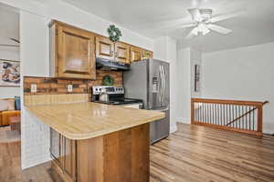 Kitchen featuring under cabinet range hood, appliances with stainless steel finishes, light wood-type flooring, light countertops, and ceiling fan