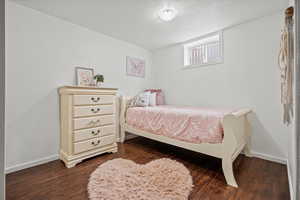 Bedroom with dark wood-style flooring and baseboards