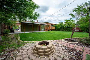View of green lawn with a fire pit and a wooden deck