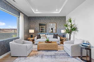 Living area with wood finished floors, recessed lighting, a tray ceiling, and baseboards
