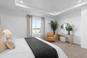 Carpeted bedroom featuring recessed lighting, a tray ceiling, and baseboards
