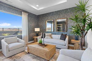 Living room with baseboards, a tray ceiling, and recessed lighting