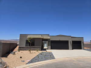 Contemporary home with stucco siding, a garage, driveway, stone siding, and a mountain view