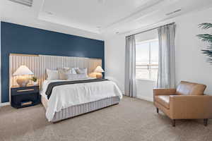 Bedroom with carpet flooring, baseboards, and a raised ceiling