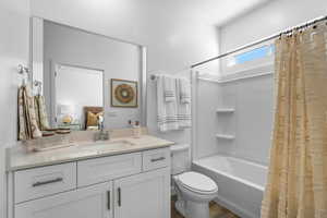 Bathroom with shower / bath combo with shower curtain, vanity, wood finished floors, and toilet
