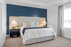 Bedroom with carpet floors, baseboards, and a tray ceiling