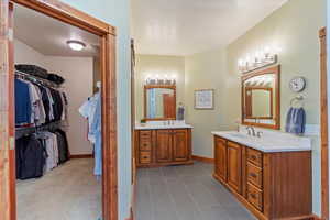 Full bath featuring, two vanities, a walk in closet, and tile flooring