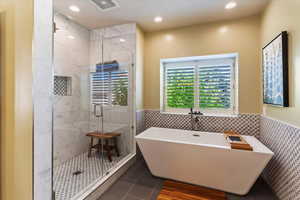 Full bathroom with tile flooring, a shower stall, and a freestanding tub