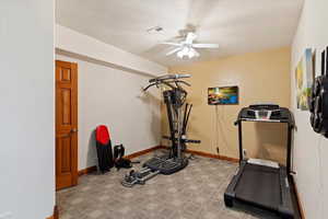 Workout room featuring a ceiling fan, carpet, and baseboards