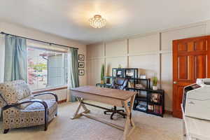 Home office with a decorative wall and light colored carpet