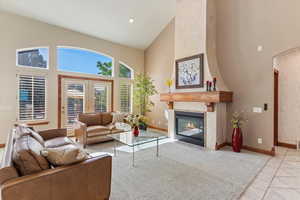 Living area featuring high vaulted ceiling, baseboards, a fireplace, light tile patterned flooring, and arched walkways