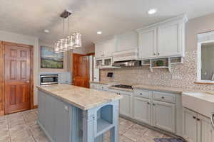 Kitchen featuring open shelves, stainless steel microwave, light tile patterned floors, premium range hood, and recessed lighting